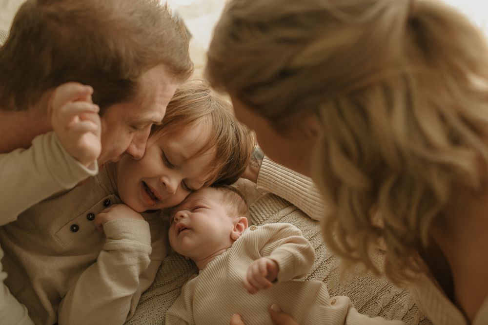 Tender family moment captured in warm tones as they cuddle together.