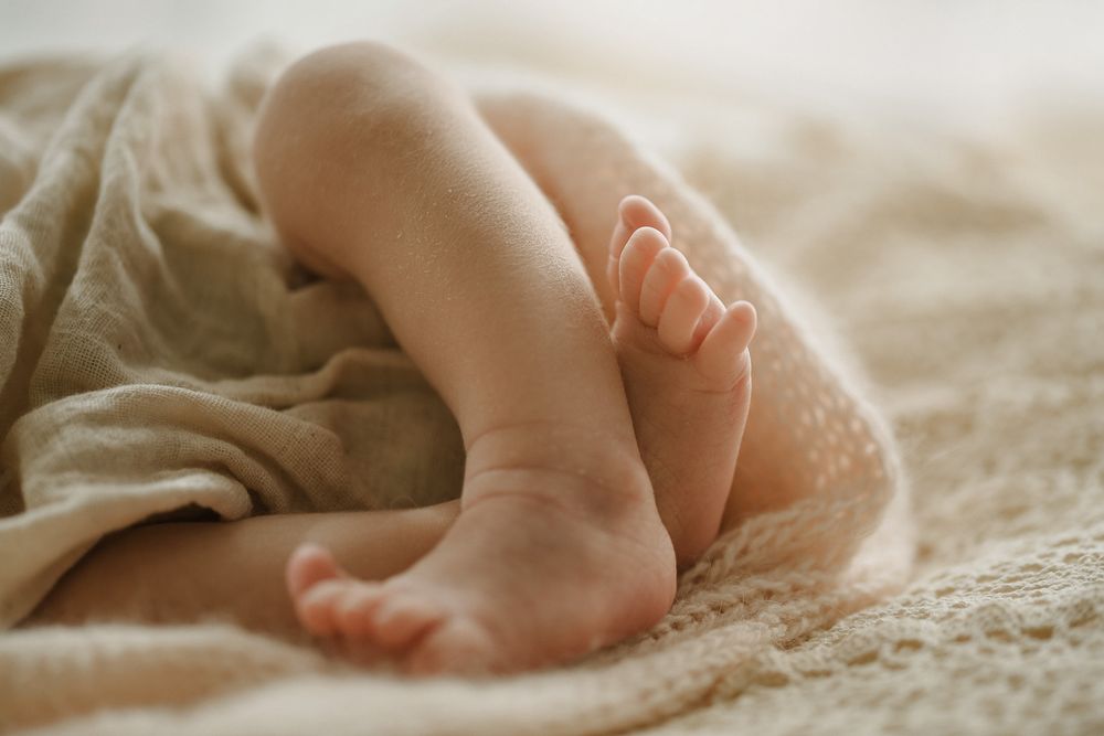 Close-up of tiny baby feet wrapped in soft beige blanket.