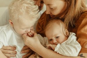 An intimate family moment with two small children and parent sharing affection in warm lighting.