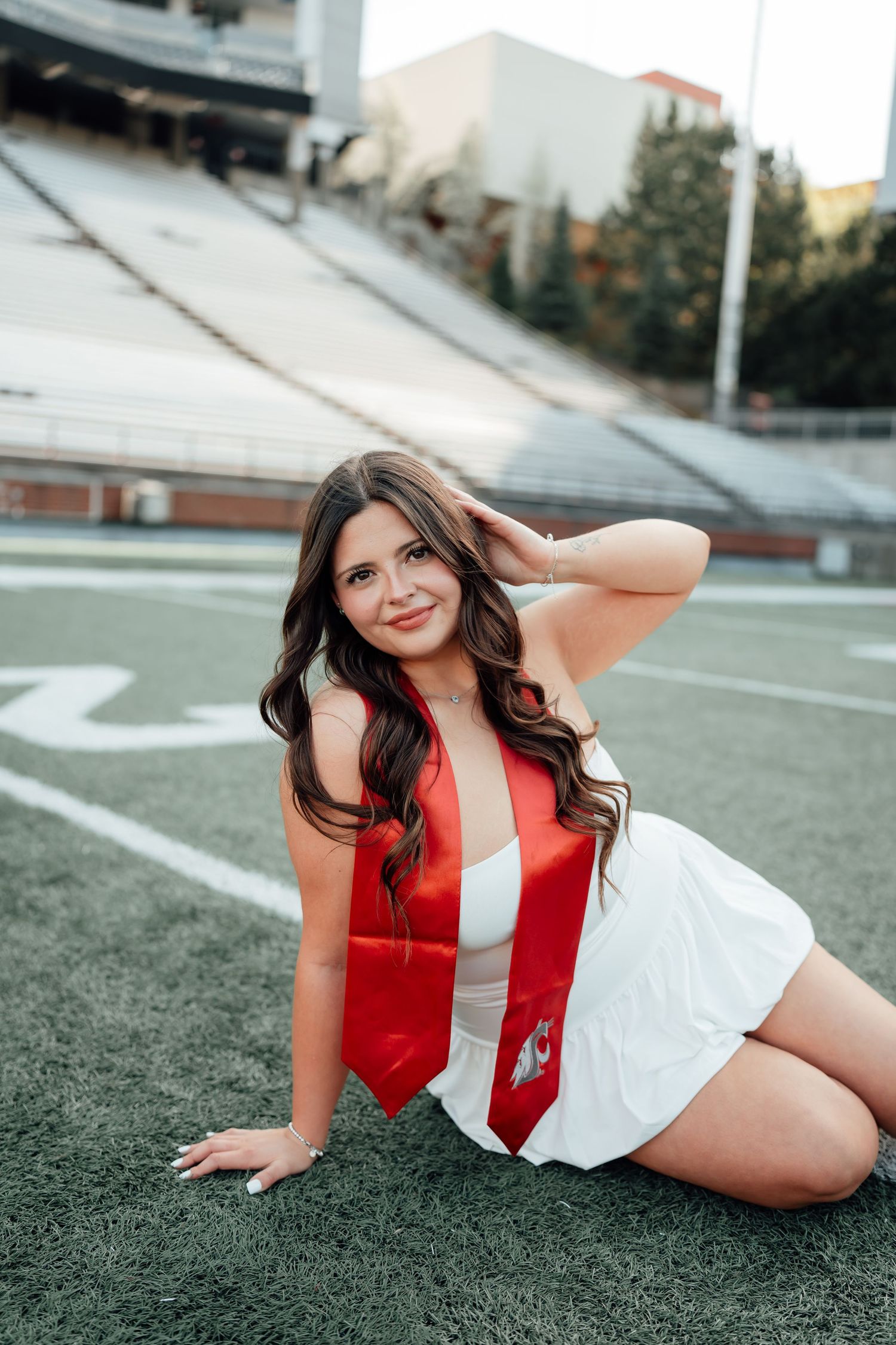 Cheerleader poses on red athletic field turf in black and red uniform.