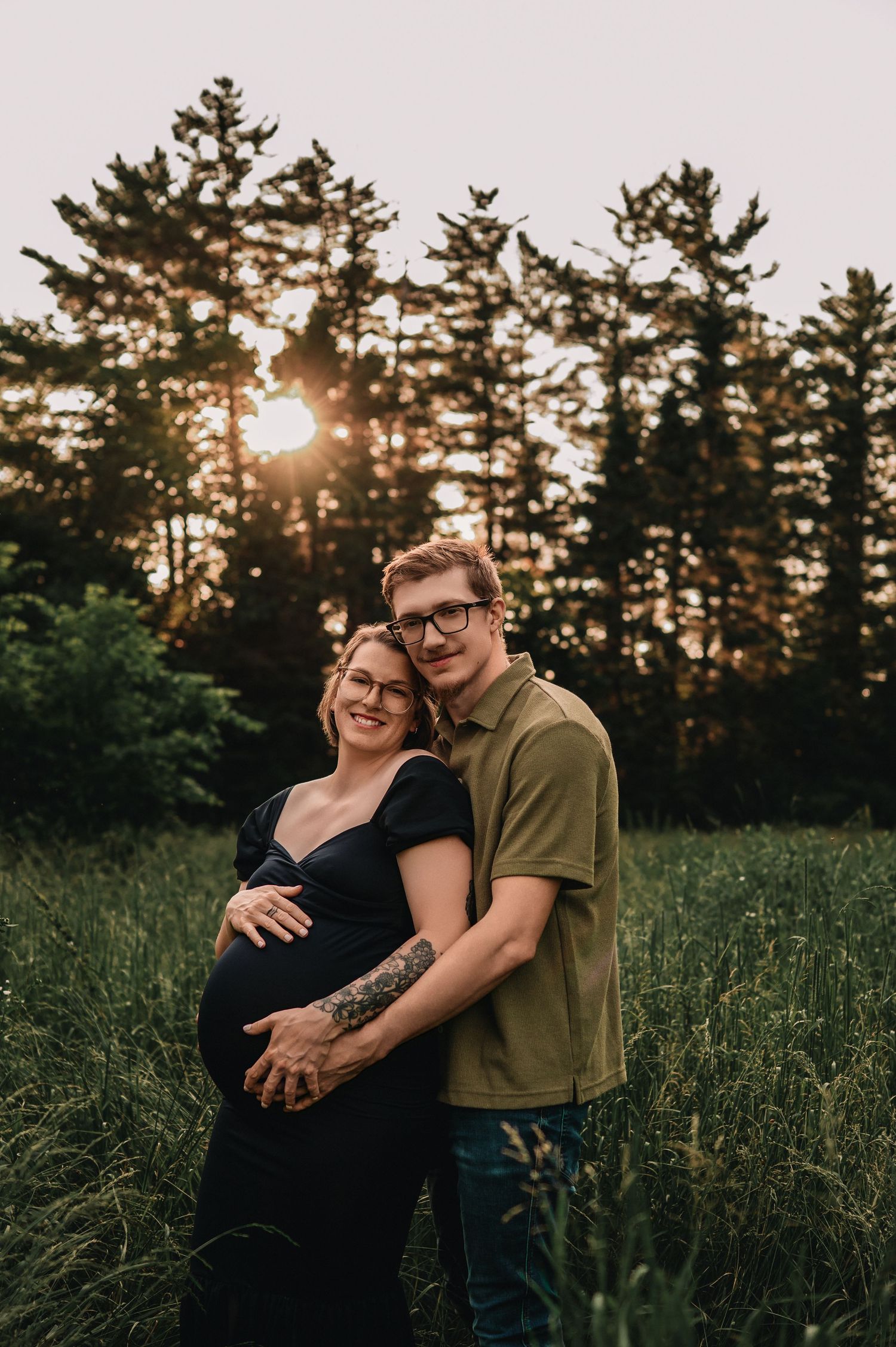 Dramatic maternity portrait with flowing red dress and crown against moody brown backdrop.