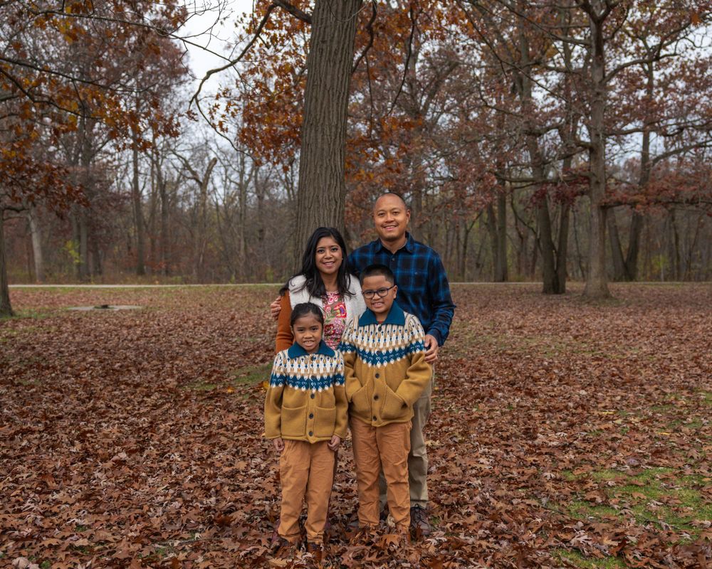 Family portrait in matching outfits standing among fall foliage.