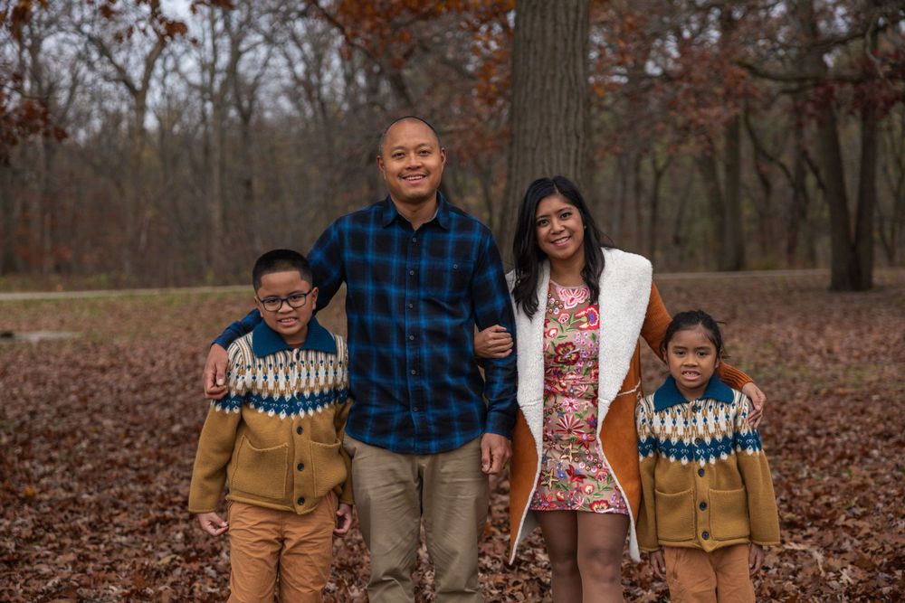 Family group photo in wooded area during fall season.