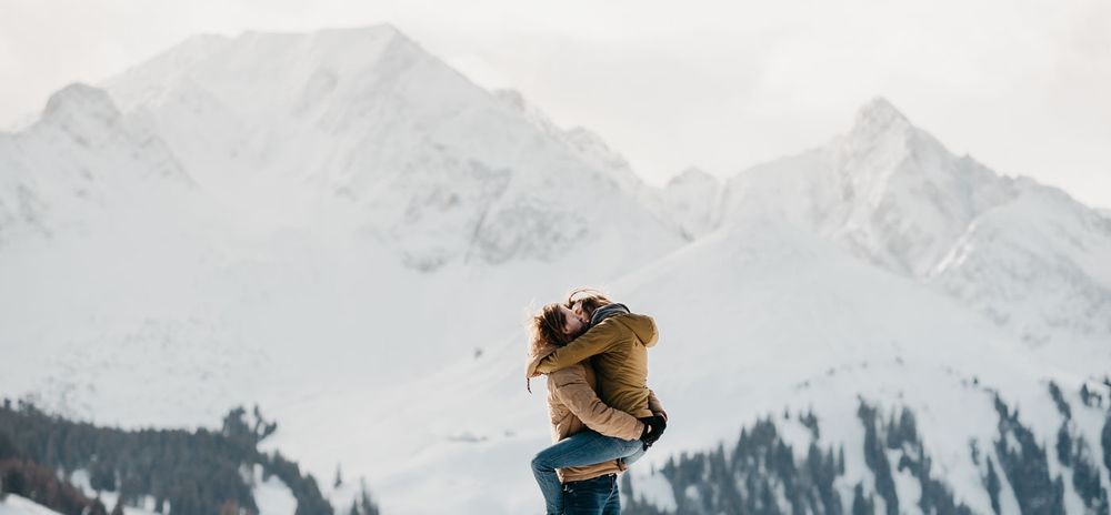 Person being lifted up against stunning snow-capped mountain backdrop in winter.