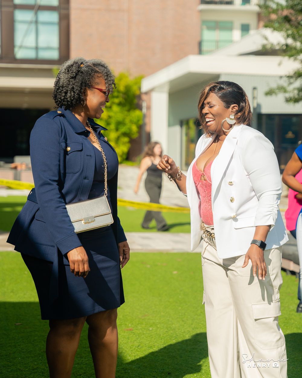 Two people engaged in animated conversation outdoors, wearing contrasting navy and white outfits.