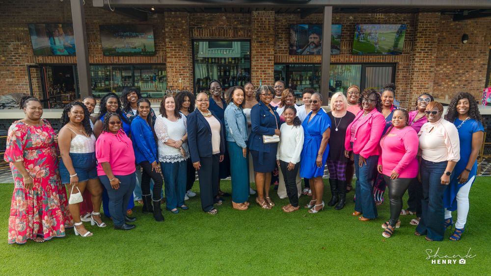 Large group photo of celebration attendees wearing colorful outfits on green lawn.