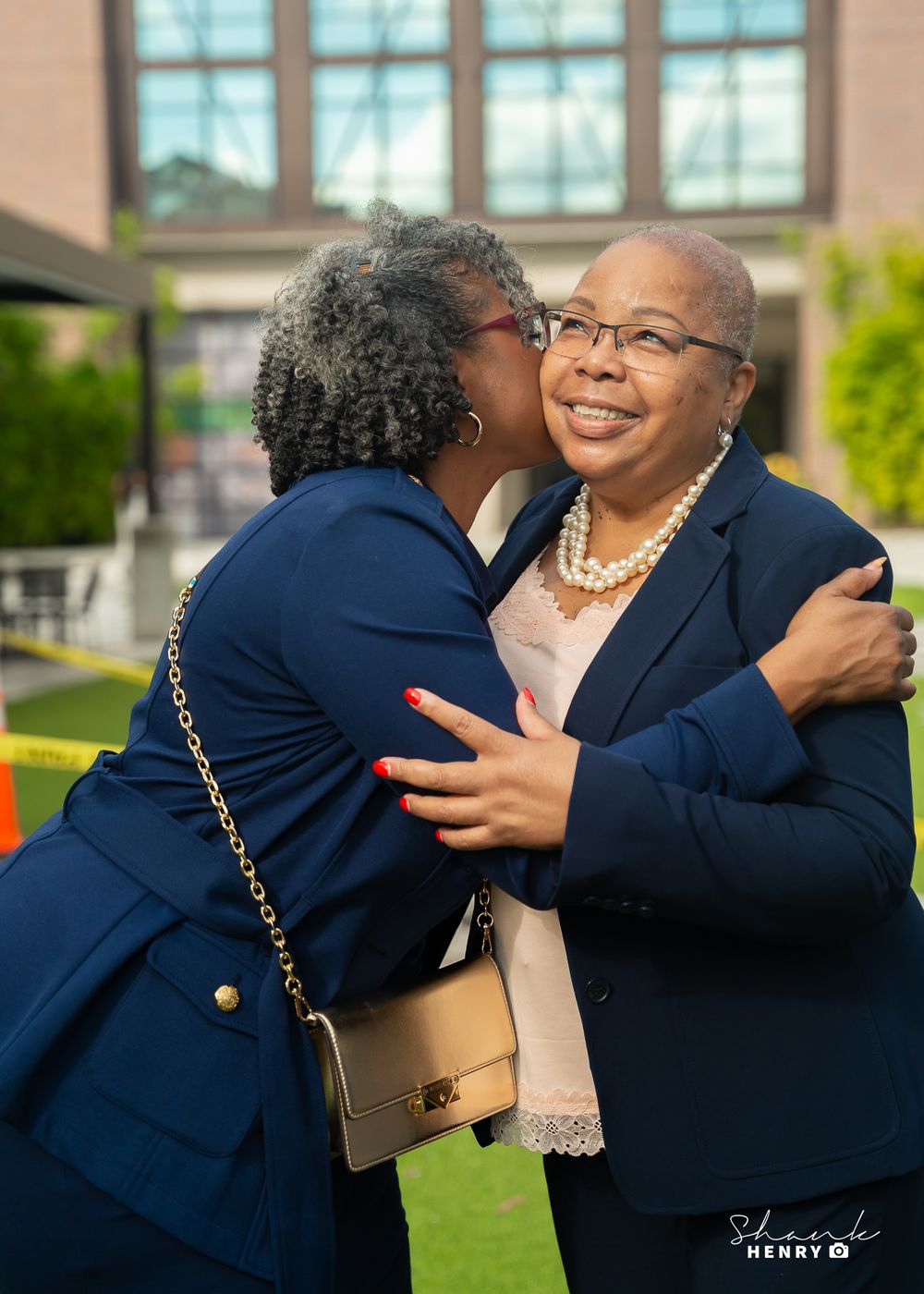 Heartwarming moment captured between two people in navy blazers sharing an embrace outdoors.