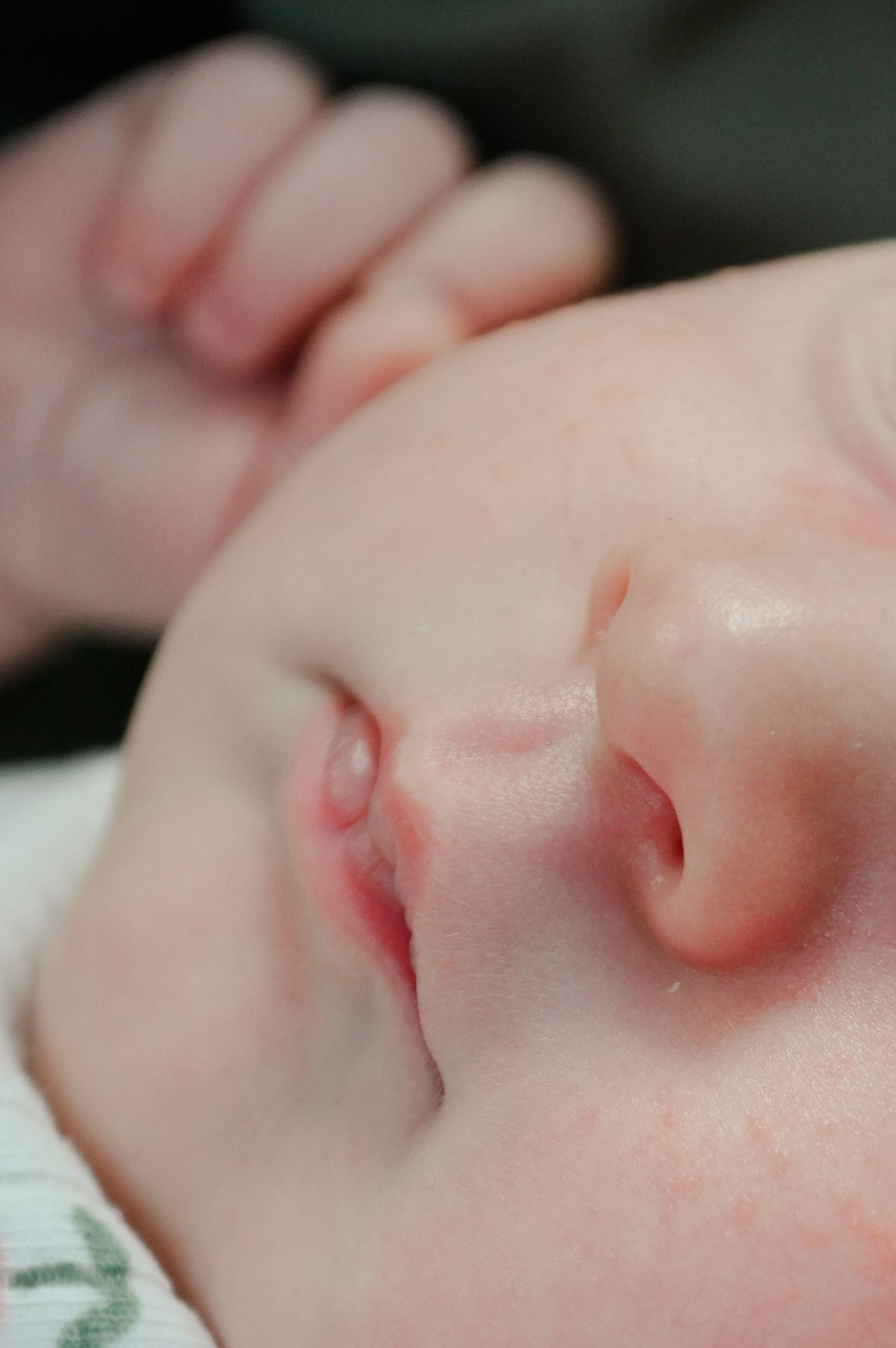 Close-up macro shot of a baby's nose and lips showing delicate pink skin and peaceful sleeping features.