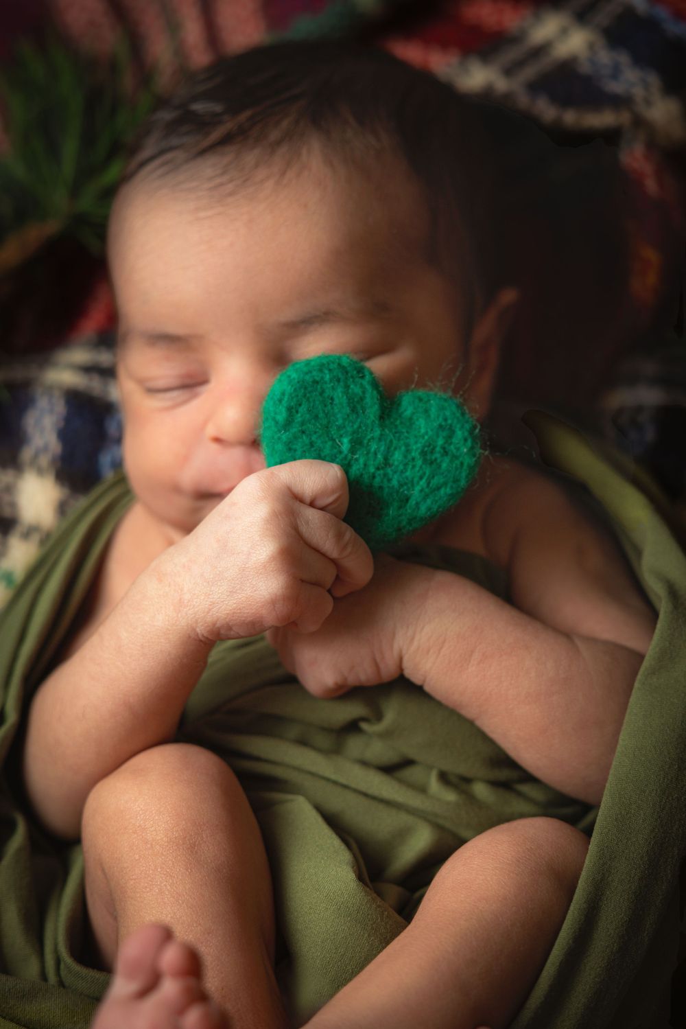 A series of photos showing a sleeping baby with a small green pom-pom on their nose in different angles.