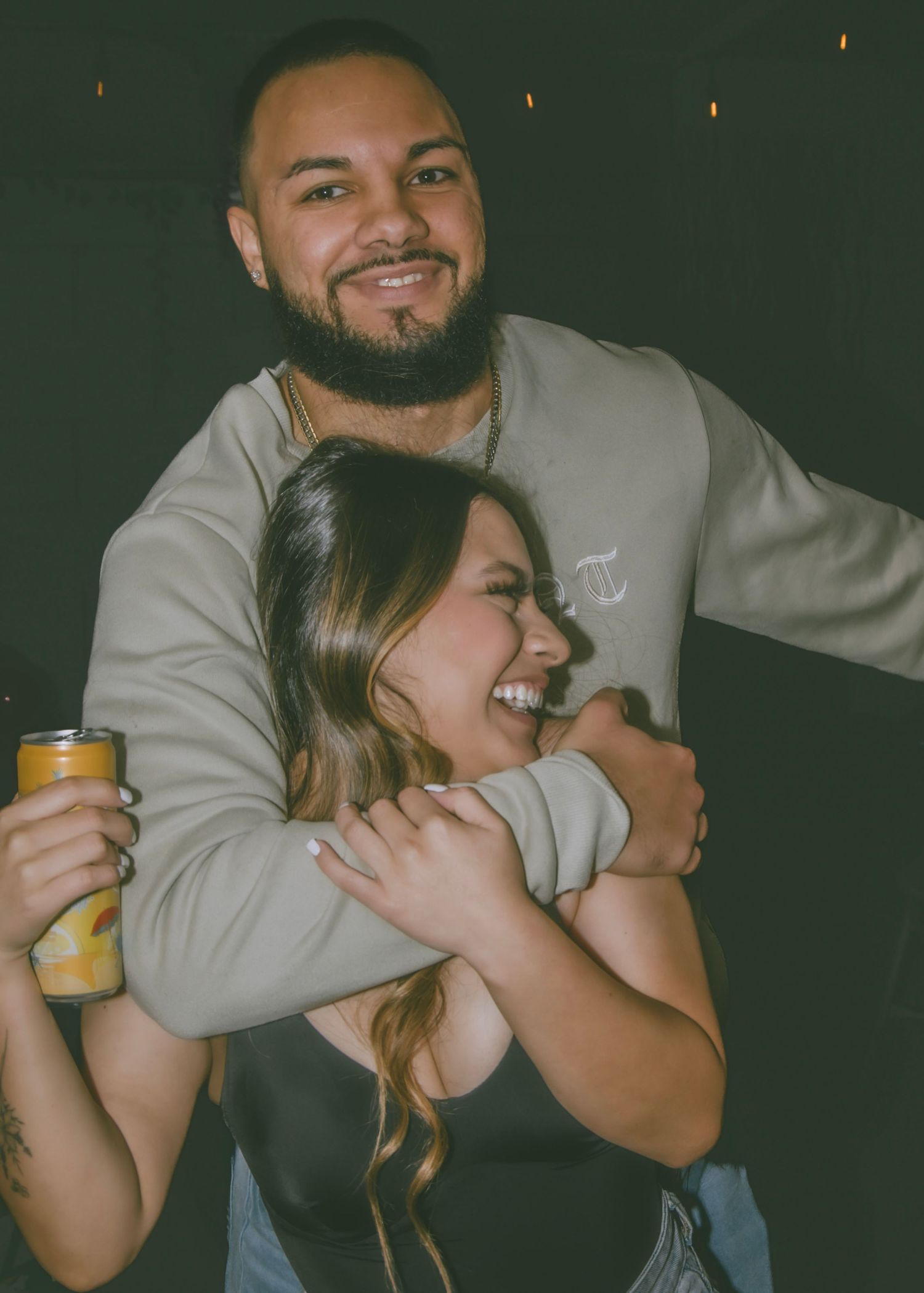 A candid moment of laughter and embrace at a social gathering.