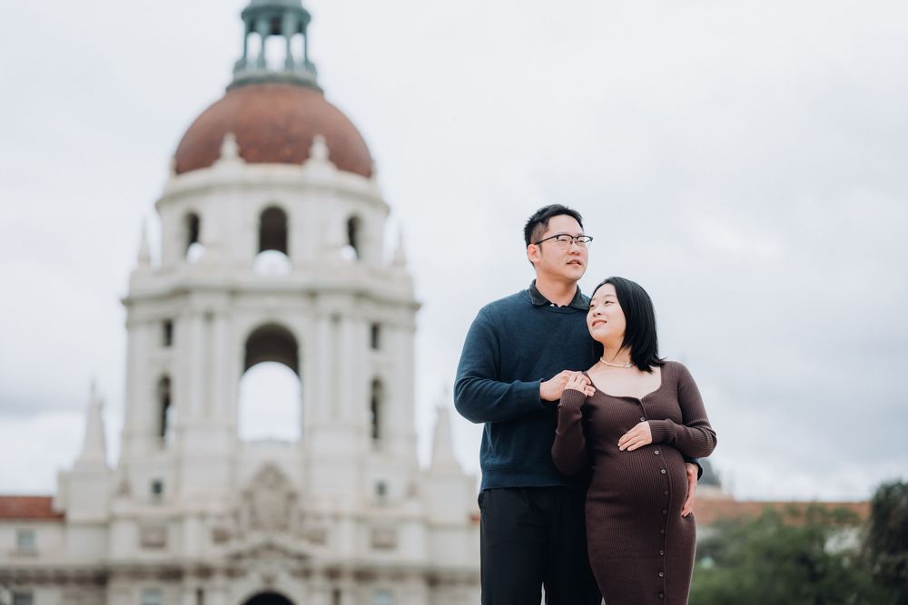 A couple shares a romantic moment in front of a white domed building during an engagement photo session.