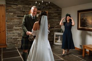 A wedding photographer captures candid moments during a ceremony in a rustic stone-walled venue.