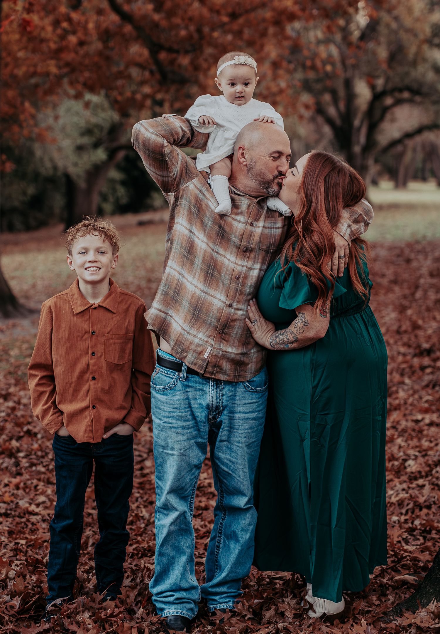 A family of four takes a portrait in autumn with falling leaves and warm colors.