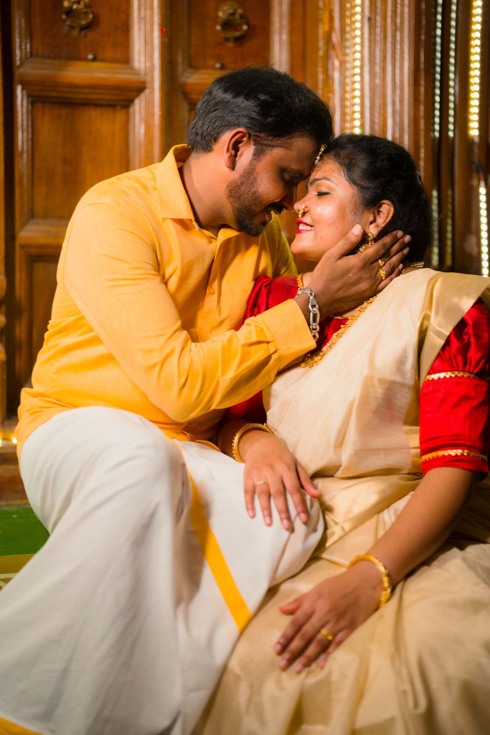 A tender moment captured in traditional Indian attire against wooden paneled walls.