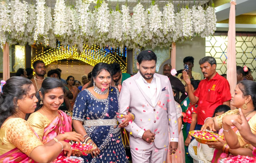 Wedding celebration under white floral decor with guests enjoying festivities in traditional attire.