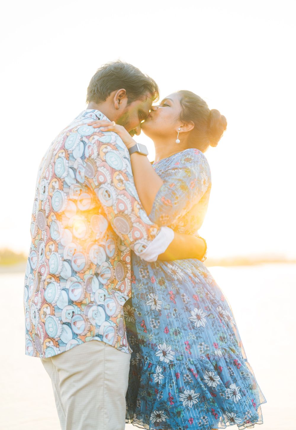 A romantic couple in matching floral prints embraces during a golden hour photoshoot.