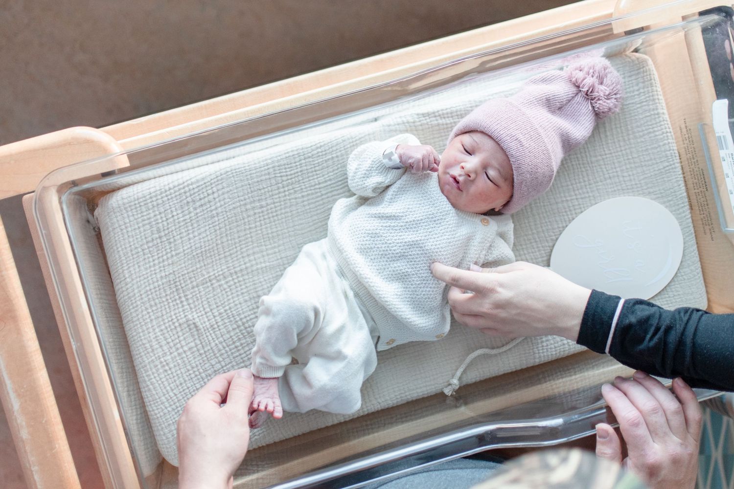Hands measuring and examining a newborn baby on a changing table.