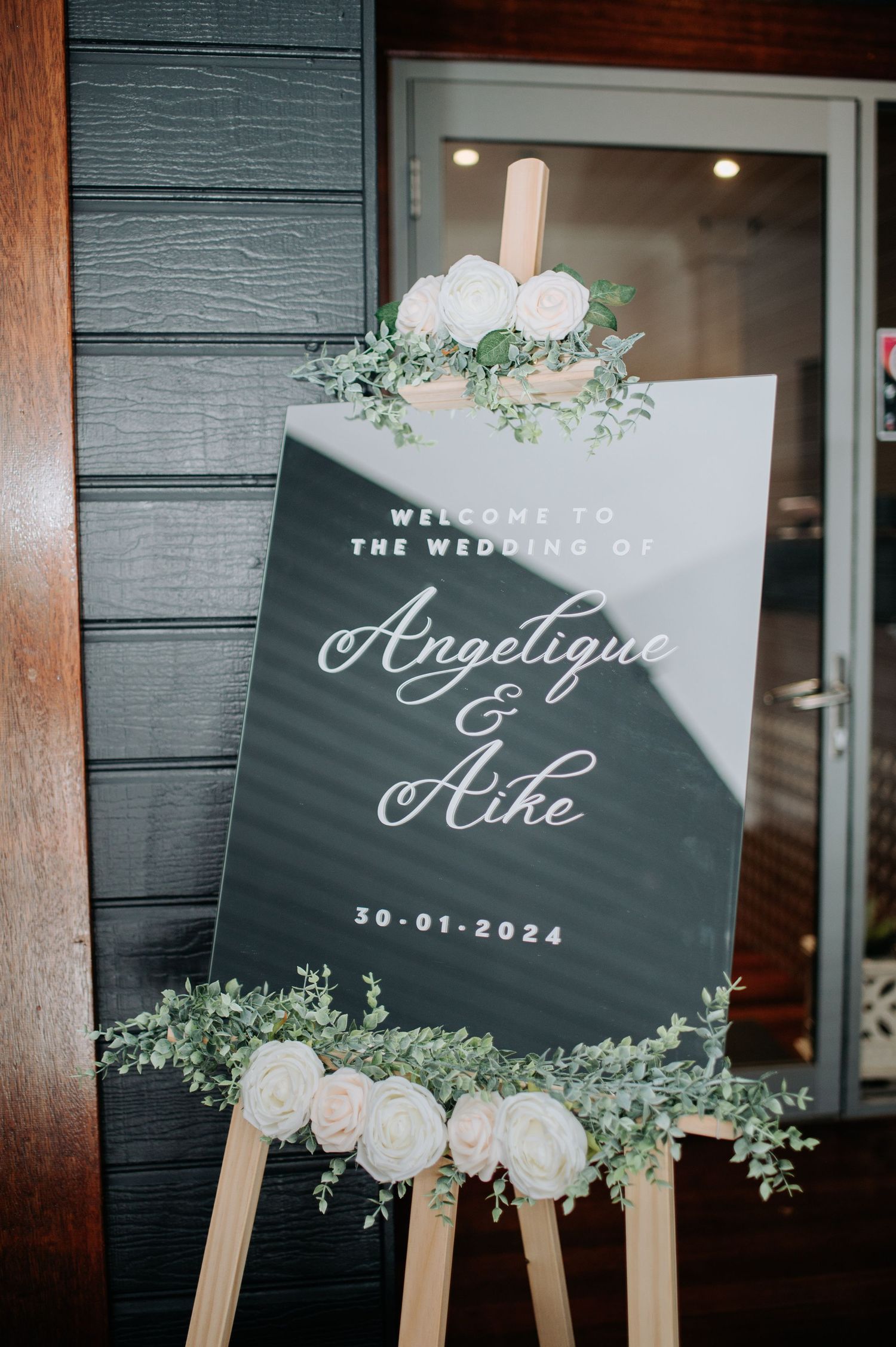 Elegant wedding welcome sign for Angelique and Mike decorated with white flowers and greenery.