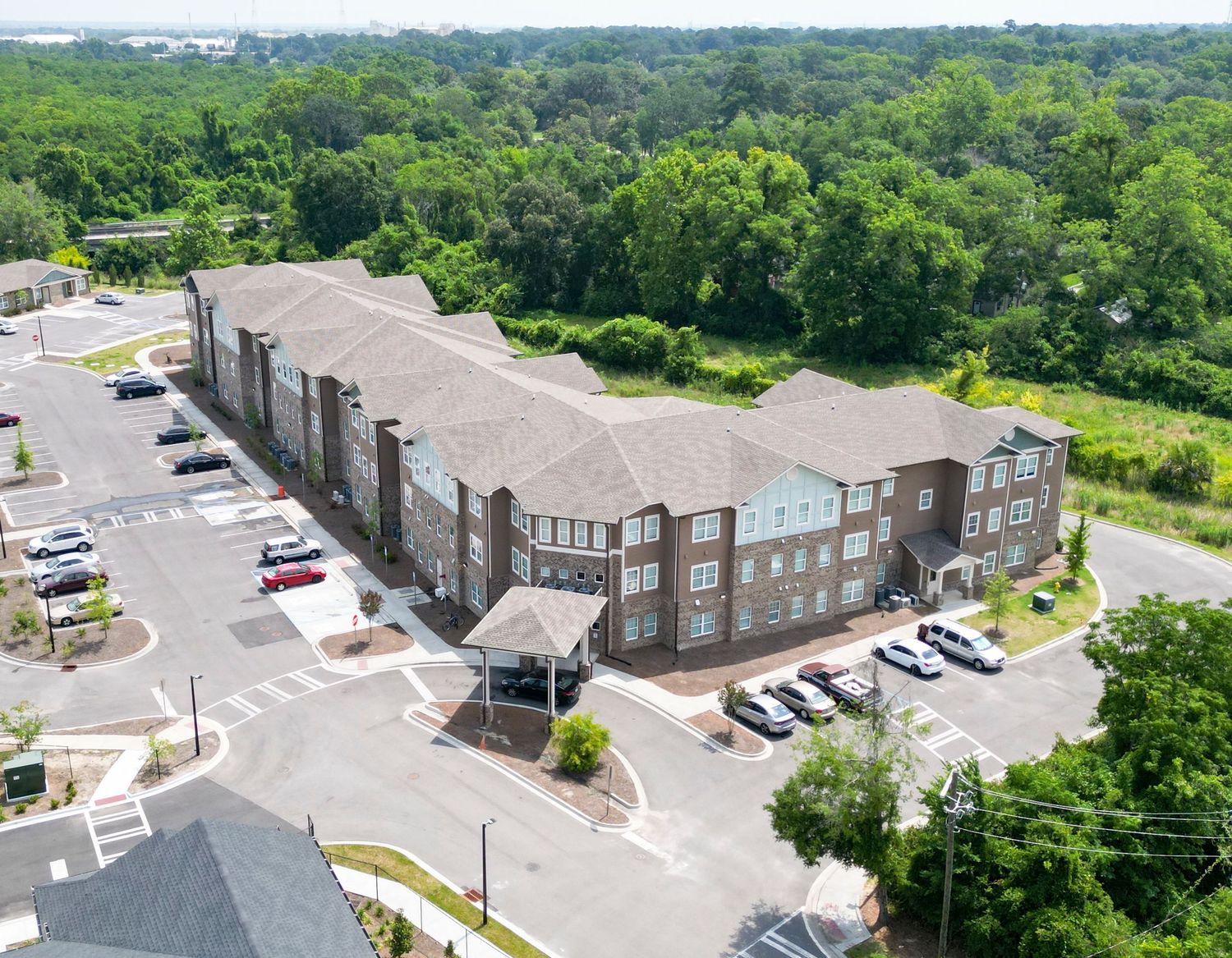 Curved apartment building complex with parking lot viewed from above.