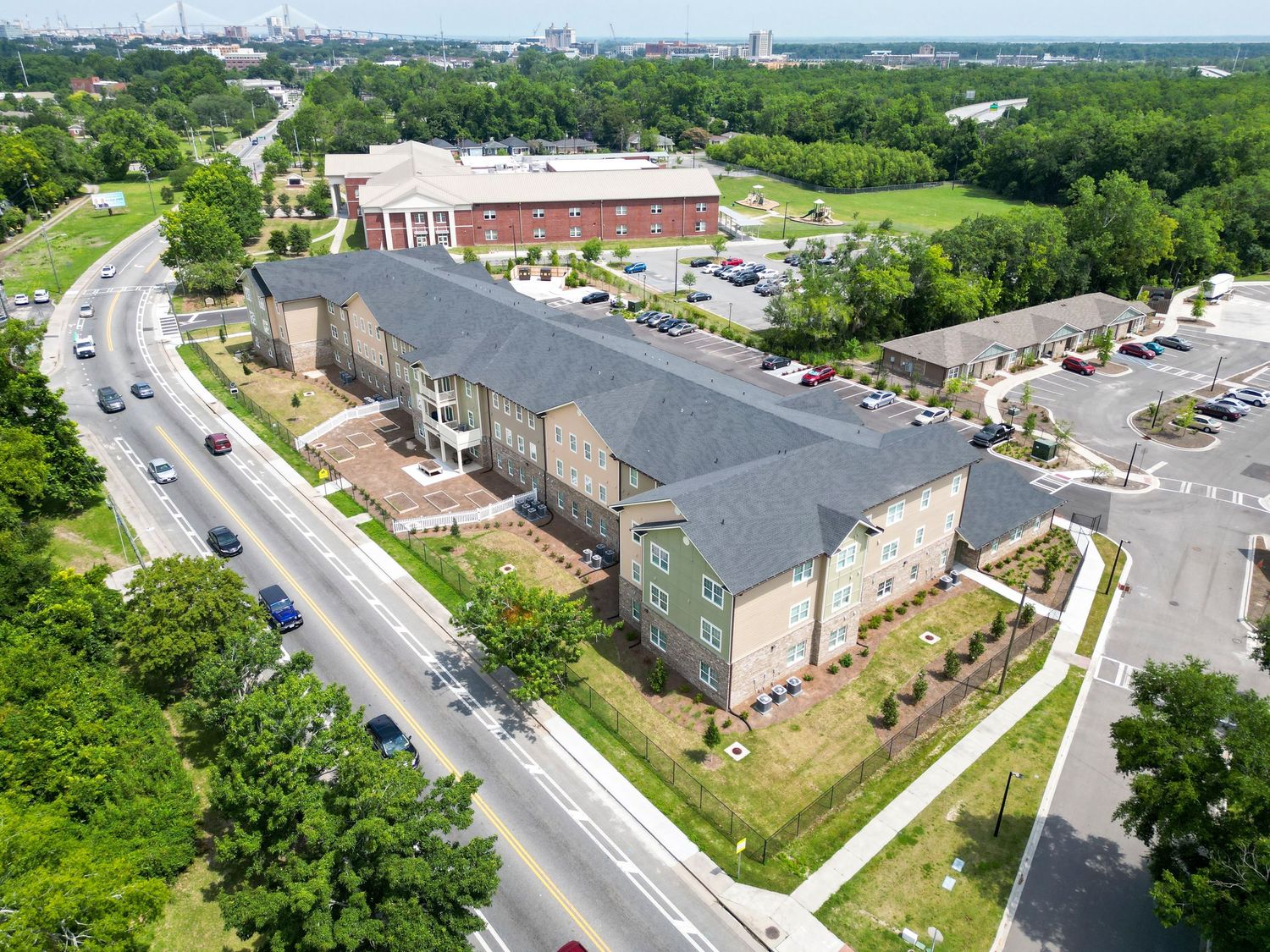 Aerial view of large residential complex with parking lot and curved road.