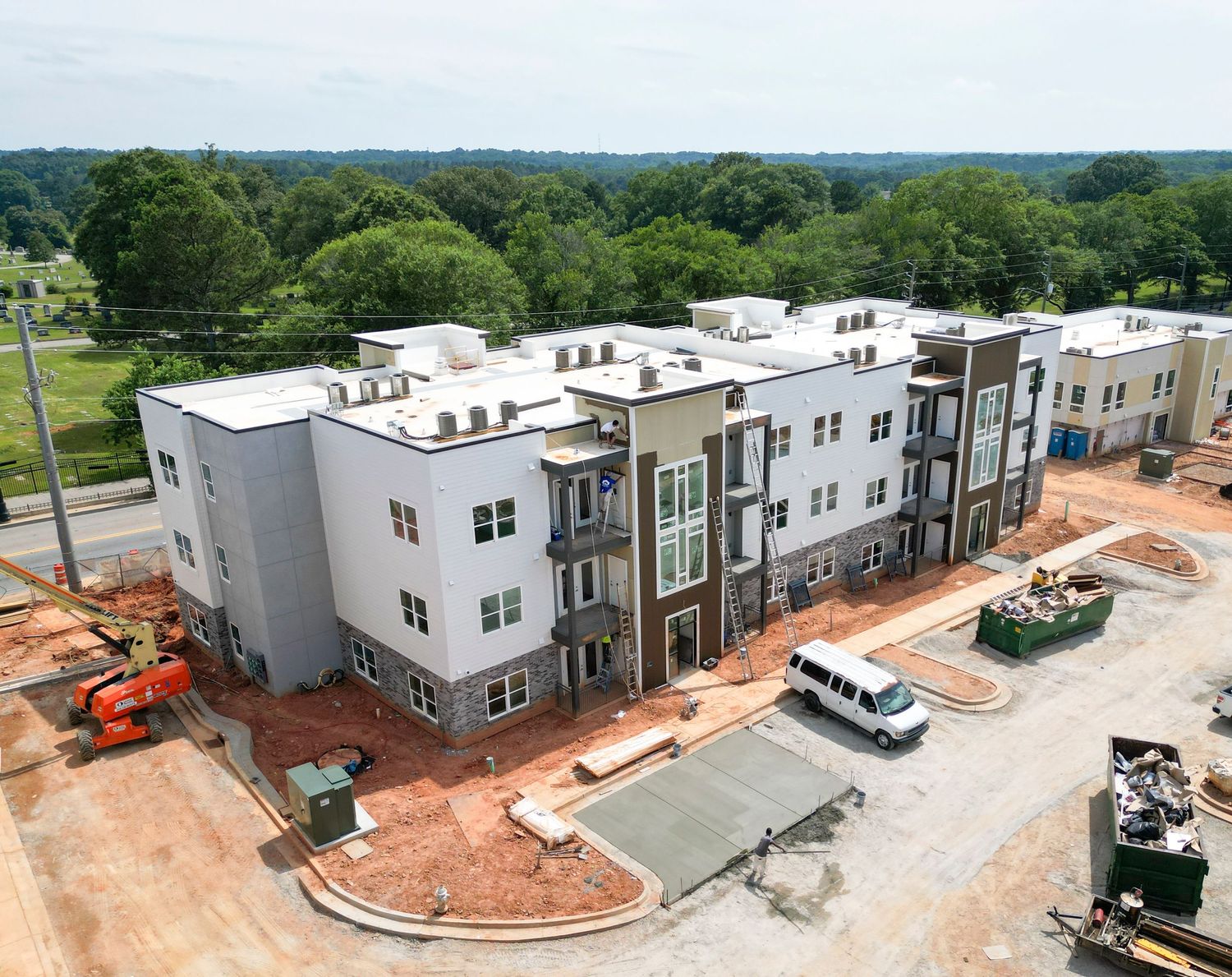 Aerial view of modern three-story apartment complex with construction vehicles visible.