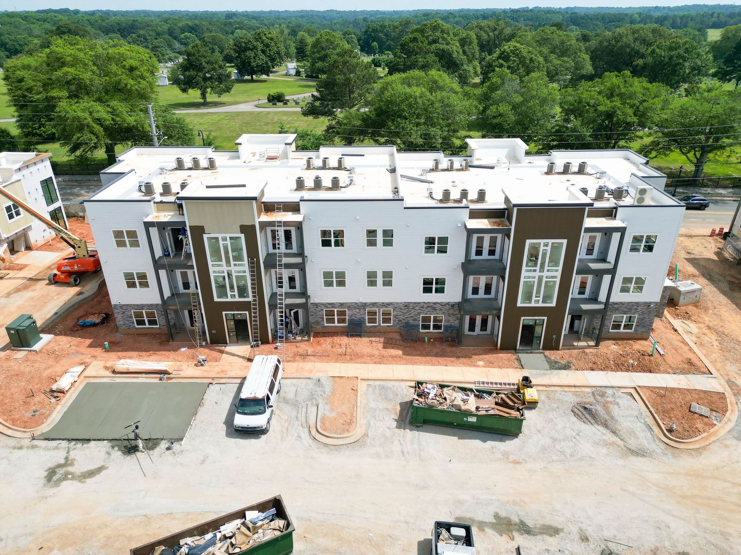 Modern multi-unit residential building with white and brown exterior nearing completion.