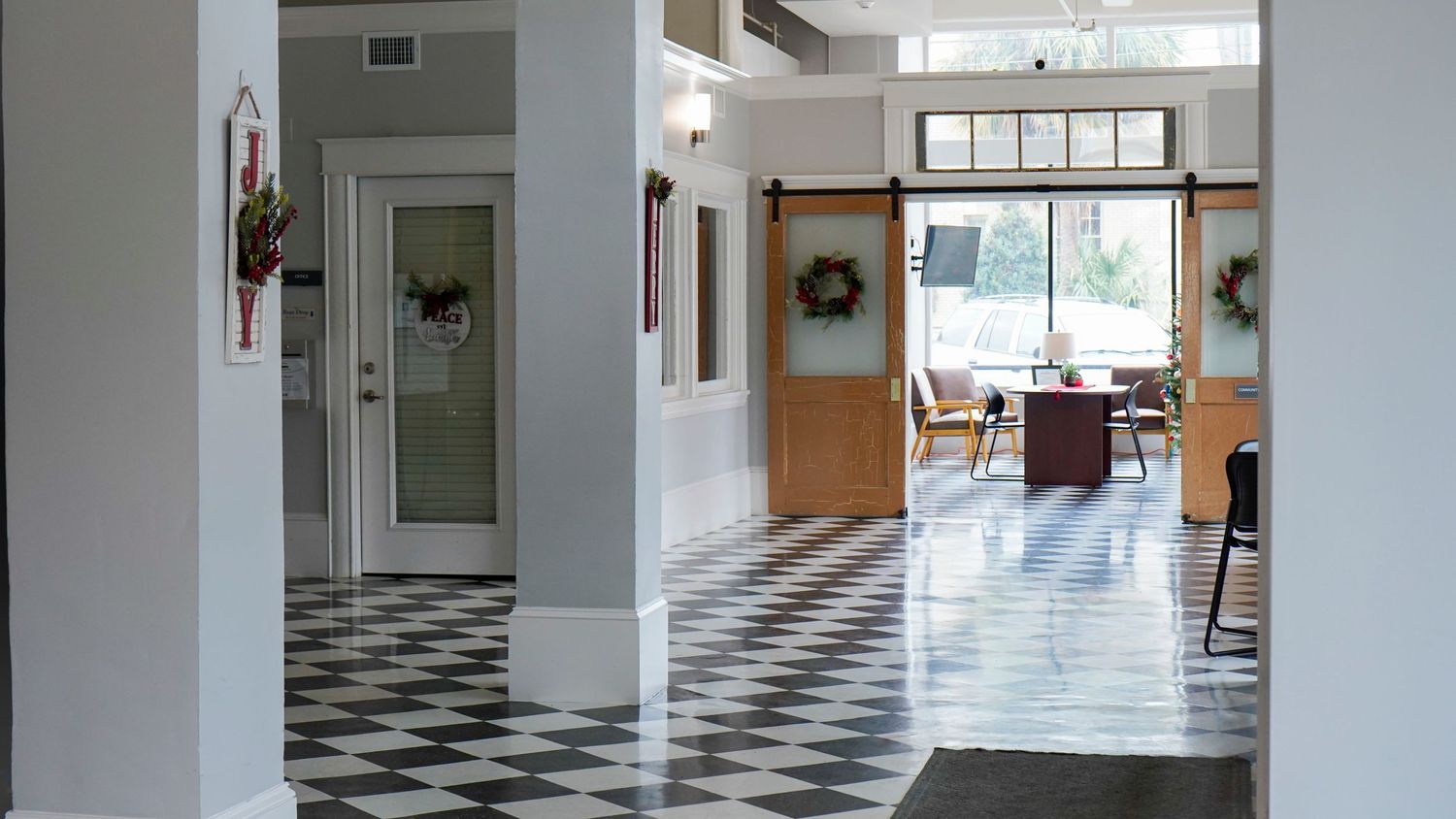 Modern interior hallway featuring black and white checkered floors and wooden doors.