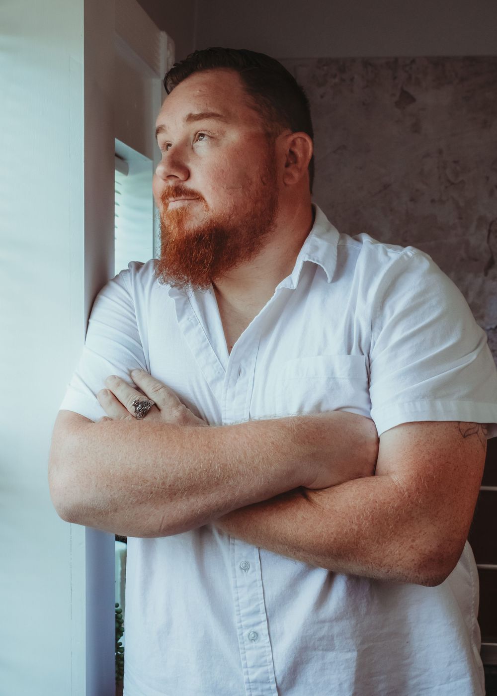 Portrait series of person in white shirt with crossed arms against light background.