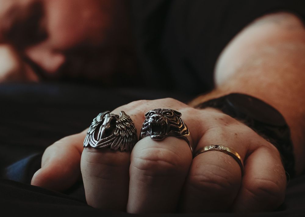 Detailed shot of multiple ornate rings on fingers in moody lighting.