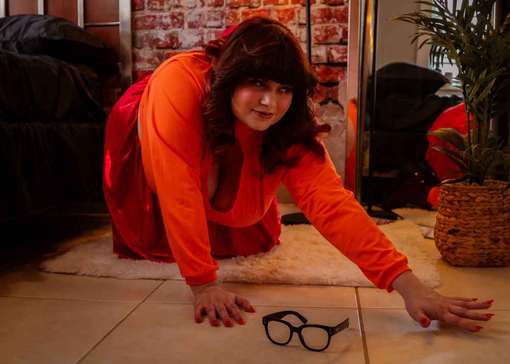 Lifestyle portrait session on floor with orange sweater and vintage-inspired decor.