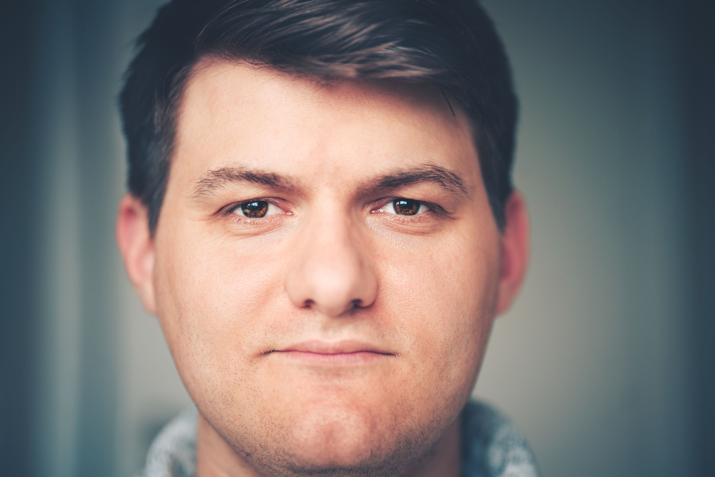 Close-up portrait against blurred teal background.