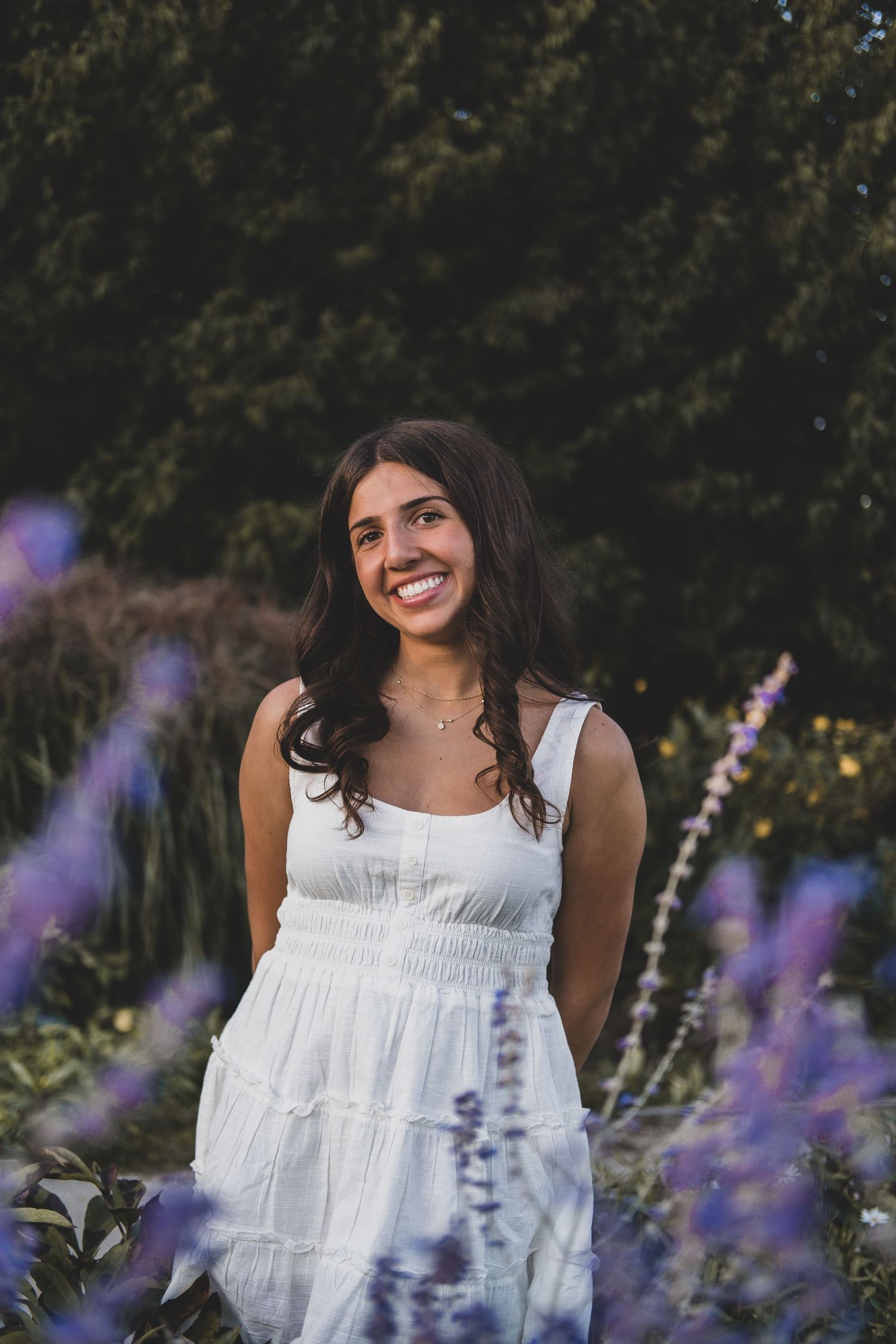 White summer dress photographed among purple lavender flowers in a garden.