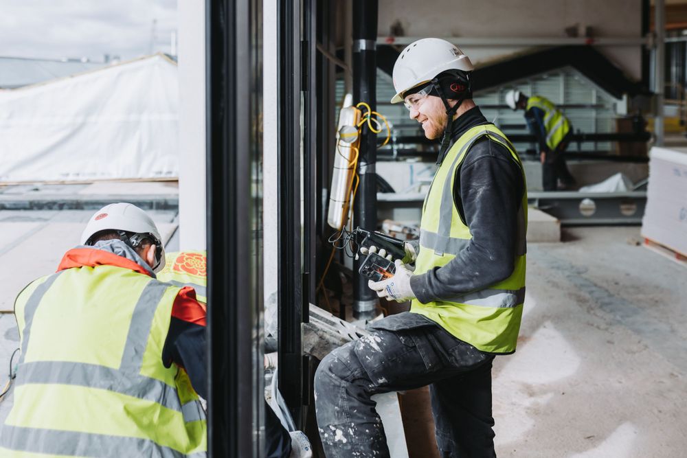Workers in safety vests and hard hats inspecting building exterior in winter conditions.