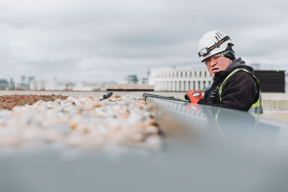 Low angle view of construction worker inspecting rooftop ventilation system.
