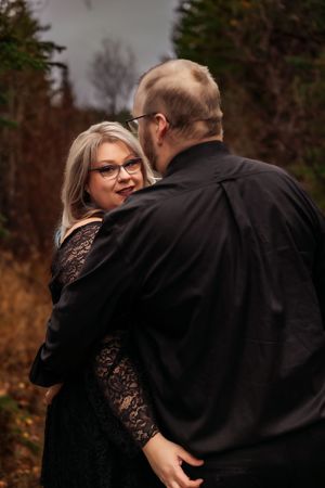 A tender embrace captured in a forest setting with autumn colors and moody lighting.