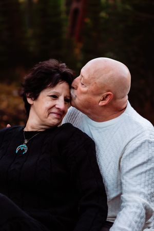 Two people share an affectionate embrace while wearing black and white sweaters outdoors.