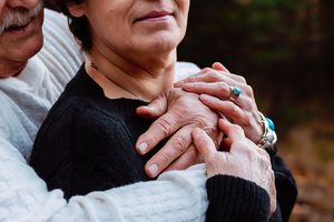 Close-up shot of hands tenderly touching during an intimate outdoor portrait session.
