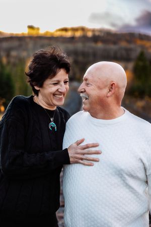A couple laughs together during an autumn photoshoot outdoors.