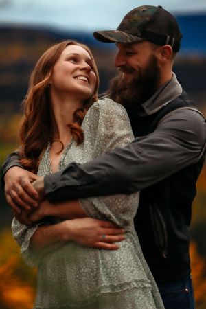 Couple shares tender moment against backdrop of autumn mountain landscape.