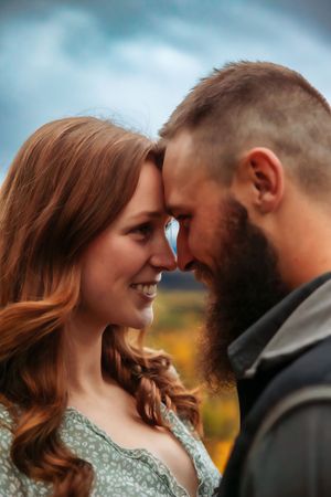 A couple shares an intimate close-up moment against a backdrop of autumn colors and mountains.