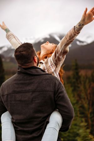 Playful piggyback ride moment captured against dramatic mountain landscape.