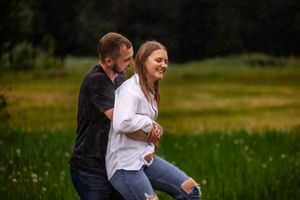 Couple embracing and laughing together in green meadow during summer day.