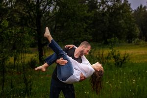 Playful couple doing romantic dip pose in flowering meadow.