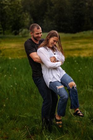 Couple laughing together while playing in green summer field.