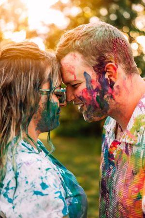 Paint-splattered couple shares tender moment in golden sunset light.
