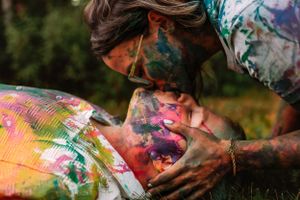 Close-up of paint-covered couple sharing intimate moment outdoors.