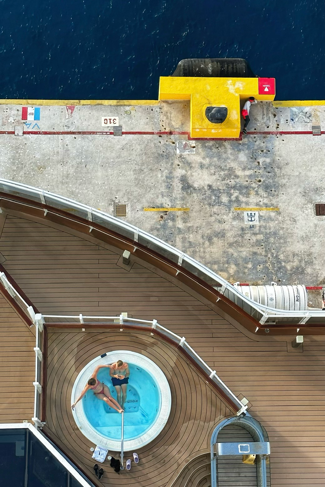 Aerial view of people relaxing in a circular pool on a cruise ship deck.
