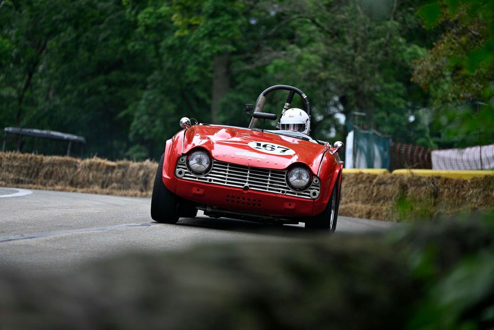 closeup of a red Triumph TR4 racing through Schenley Park during the Pittsburgh Vintage Grand Prix.