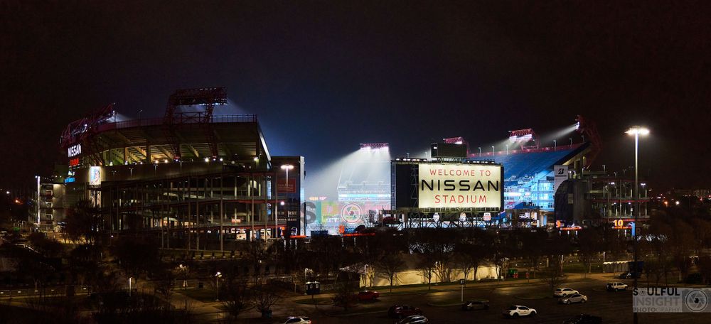 Modern stadium lit up at night with Nissan signage visible on exterior.