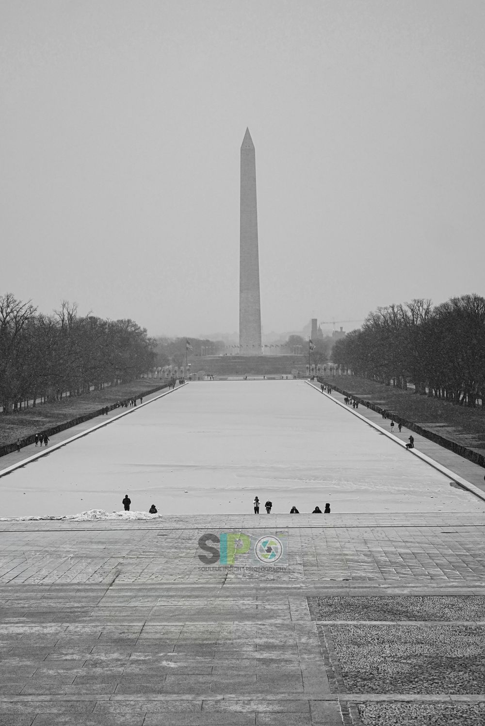 Washington Monument in winter with reflecting pool covered in snow.